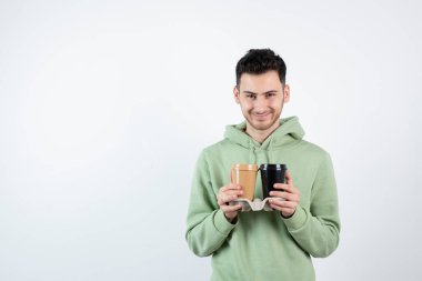Ellerindeki kahve fincanlarına bakan genç bir adam resmi. Yüksek kalite fotoğraf
