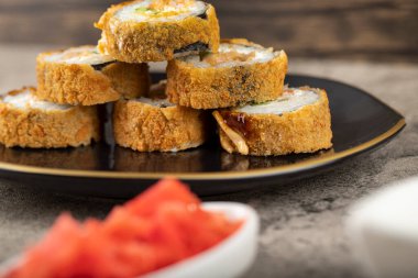 Siyah suşi ruloları ve taş bir masaya yerleştirilmiş zencefil dilimleri. Yüksek kalite fotoğraf