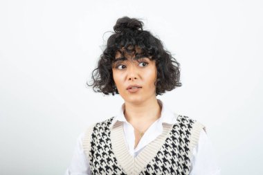 Beyazın üzerinde duran ve poz veren kıvırcık bir kadın resmi. Yüksek kalite fotoğraf