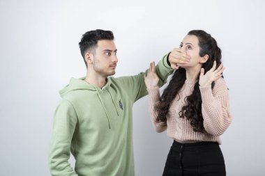 Esmer adam genç kadın mankene elleriyle ağzını kapatıyor. Yüksek kalite fotoğraf