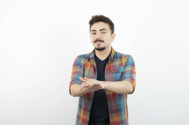 Kareli tişört giymiş ve beyaz duvarın üzerinde duran yakışıklı bir adam resmi. Yüksek kalite fotoğraf