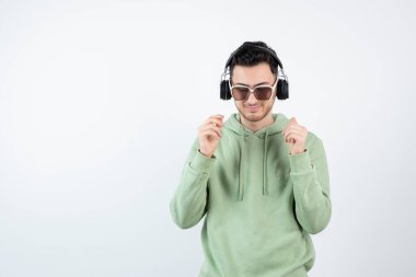 Kulaklıklı genç yakışıklı bir adamın beyazın üzerinde duruşu. Yüksek kalite fotoğraf