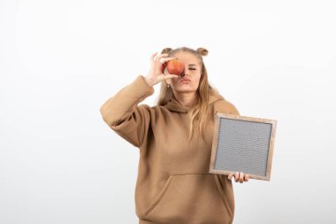 Kırmızı elmayı ve beyaz çerçeveyi gösteren genç bir kadın resmi. Yüksek kalite fotoğraf