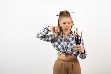 Kadın sanatçı baş parmağını indiriyor ve elinde fırça tutuyor. Yüksek kalite fotoğraf