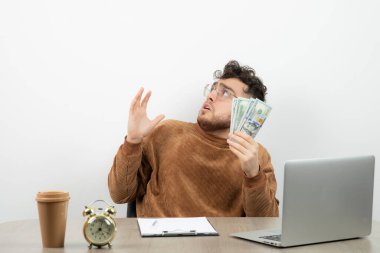 Genç yakışıklı işadamı masasında oturuyor ve elinde para var. Yüksek kalite fotoğraf