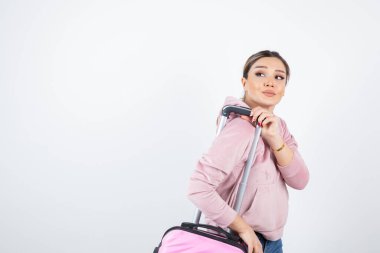 Pembe kapüşonlu, bavullu çekici bir kadın seyahate çıkıyor. Yüksek kalite fotoğraf