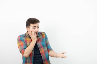 Şok olmuş, kareli tişörtlü, yanaklı yakışıklı bir adam resmi. Yüksek kalite fotoğraf