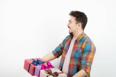 Beyaz bir duvarın üzerinde hediye kutuları tutan çekici bir adamın portresi. Yüksek kalite fotoğraf