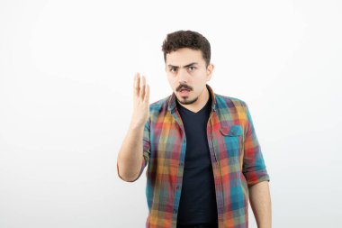 Kareli tişört giymiş ve beyaz duvarın üzerinde duran yakışıklı bir adam resmi. Yüksek kalite fotoğraf