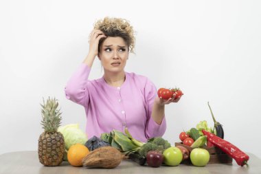 Masada çeşitli meyve ve sebzelerle poz veren güzel bir kadın.