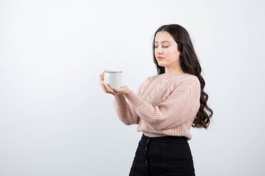 Genç esmer kadın beyaz arka planda bir fincan sıcak kahve tutuyor. Yüksek kalite fotoğraf