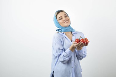 Mavi şallı güzel bir kadın elinde kırmızı taze domates tutuyor. Yüksek kalite fotoğraf