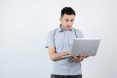 Bilgisayarı beyaz duvarın üstünde tutan genç adamın portresi. Yüksek kalite fotoğraf