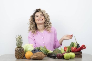 Masada çeşitli meyve ve sebzelerle poz veren güzel bir kadın.