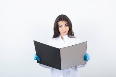 Esmer doktorun beyaz duvardan hasta kayıtlarını okuduğu fotoğraf. Yüksek kalite fotoğraf