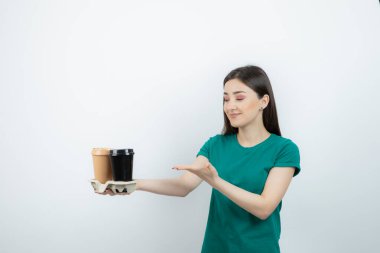 Mavi tişörtlü, kahve fincanı gösteren güzel bir kadın fotoğrafı. Yüksek kalite fotoğraf