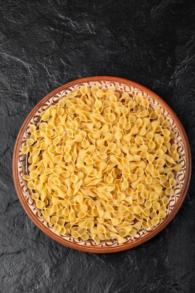 Brown Plate Raw Macaroni Placed Black Background High Quality Photo — Stock Photo, Image