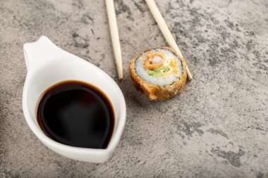 Soya soslu suşi rulosu ve taş masaya konmuş tek kullanımlık ahşap çubuklar. Yüksek kalite fotoğraf