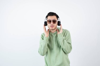 Kulaklıklı genç yakışıklı bir adamın beyazın üzerinde duruşu. Yüksek kalite fotoğraf
