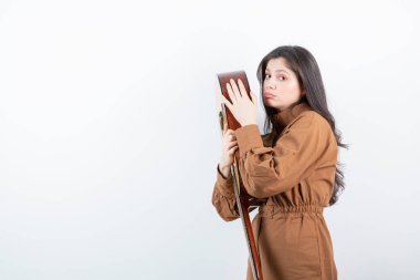 Beyaz duvarda gitara sarılan esmer bir kadın modeli. Yüksek kalite fotoğraf