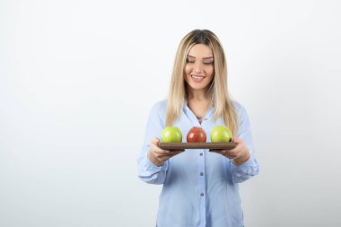 Tahtada yeşil ve kırmızı elmalar tutan sarışın bir kızın portresi. Yüksek kalite fotoğraf