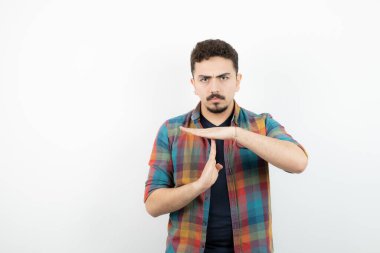 Kareli tişörtlü genç yakışıklı bir adam zaman aşımı hareketi gösteriyor. Yüksek kalite fotoğraf