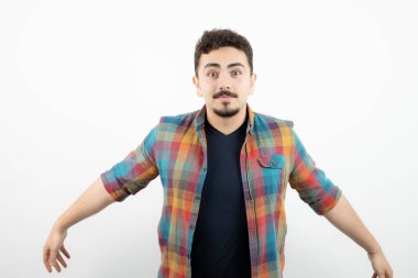 Kareli tişört giymiş ve beyaz duvarın üzerinde duran yakışıklı bir adam resmi. Yüksek kalite fotoğraf