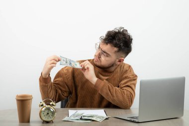Erkek ofis çalışanı masada oturuyor ve paraya bakıyor. Yüksek kalite fotoğraf