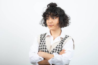 Kollarını beyazın üzerinde birleştirmiş kıvırcık genç bir kadın görüntüsü. Yüksek kalite fotoğraf