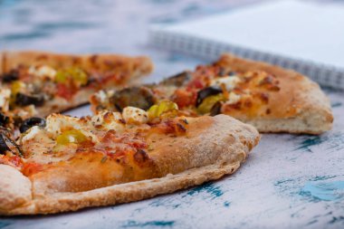 Sebzeli dilimlenmiş lezzetli pizza ve mermer masada boş defter. Yüksek kalite fotoğraf