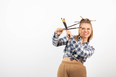 Beyaz bir duvarın üzerinde fırça tutan ve poz veren genç bir sanatçının portresi. Yüksek kalite fotoğraf