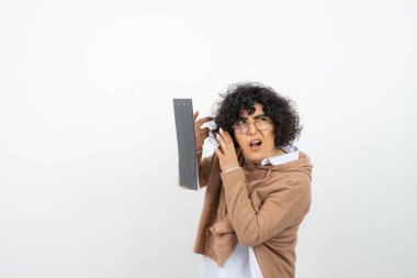 Bukleli siyah saçlı, pano ile poz veren genç bir kadın.