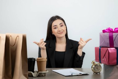 İş yerinde elinde hediyelerle oturan iş kadınının portresi.