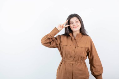 Beyaz duvara karşı zafer işareti gösteren esmer bir kadın modeli. Yüksek kalite fotoğraf