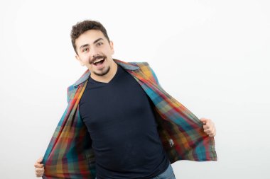 Kareli tişört giymiş ve beyaz duvarın üzerinde duran yakışıklı bir adam resmi. Yüksek kalite fotoğraf