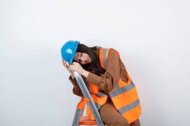 Miğferli kadın mühendis merdivenin tepesinde uyuyor. Yüksek kalite fotoğraf