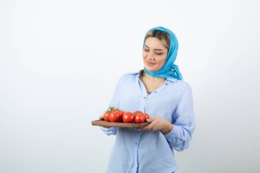 Mavi şallı güzel bir kadının portresi. Elinde ahşap bir tahta domates var. Yüksek kalite fotoğraf