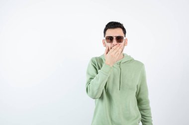 Gözlüklü yakışıklı adamın ayakta ve ağzını tutarken görüntüsü. Yüksek kalite fotoğraf