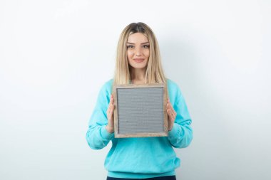 Beyaz duvara çerçeveyi dayamış güzel bir bayan portresi. Yüksek kalite fotoğraf