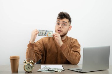 Genç yakışıklı işadamı masasında oturuyor ve elinde para var. Yüksek kalite fotoğraf