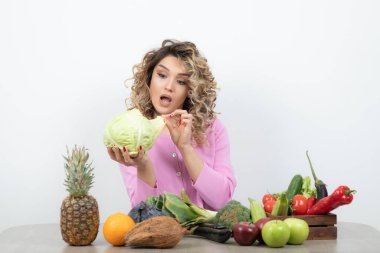 Masada çeşitli meyve ve sebzelerle poz veren güzel bir kadın.