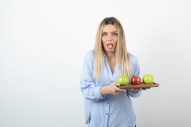 Tahtada yeşil ve kırmızı elmalar tutan sarışın bir kızın portresi. Yüksek kalite fotoğraf