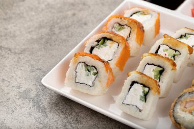 Beyaz tabak, taştan arka planda çeşitli suşi ruloları. Yüksek kalite fotoğraf