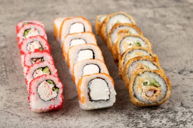 Taştan arka planda taze balıklı çeşitli suşi ruloları. Yüksek kalite fotoğraf
