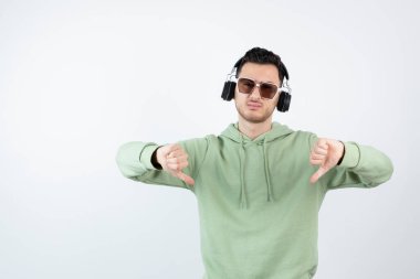 Kulaklıklı genç yakışıklı bir adamın baş parmağını kaldırması. Yüksek kalite fotoğraf