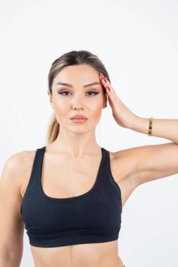 Siyah spor elbiseli sarışın kadın beyaz bir duvarın üzerinde dikilip poz veriyor. Yüksek kalite fotoğraf