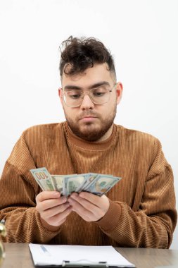 Genç muhasebeci masasında oturmuş paraları sayıyor. Yüksek kalite fotoğraf