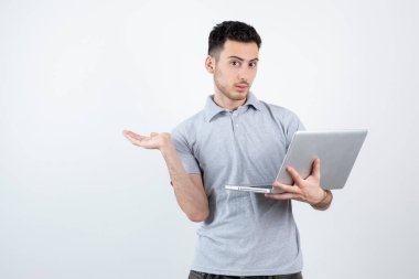 Bilgisayarı beyaz duvarın üstünde tutan genç adamın portresi. Yüksek kalite fotoğraf