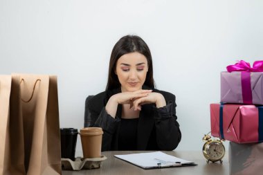 İş yerinde elinde hediyelerle oturan iş kadınının portresi.