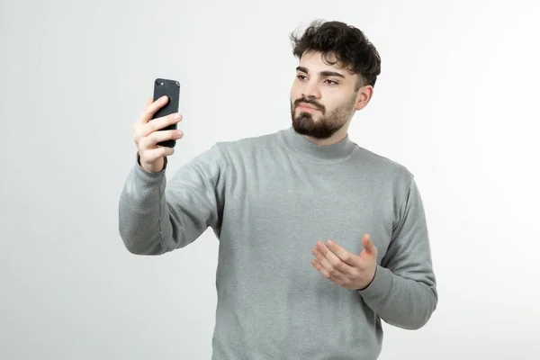 Portret Atrakcyjnego Faceta Trzymającego Smartfon Pod Białą Ścianą Wysokiej Jakości — Zdjęcie stockowe